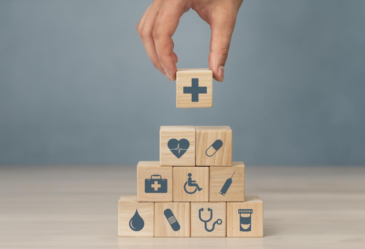 Hand bouwt toren van blokjes met pictogrammen gerelateerd aan de gezondheidszorg